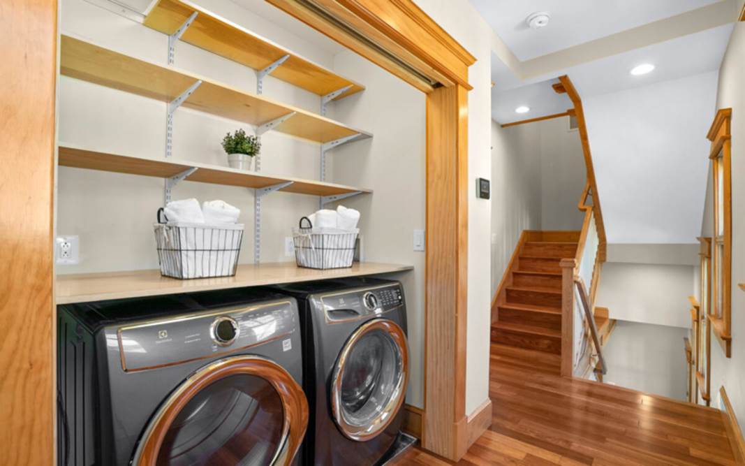 A laundry room with a wood floor and a wood shelf

Description automatically generated