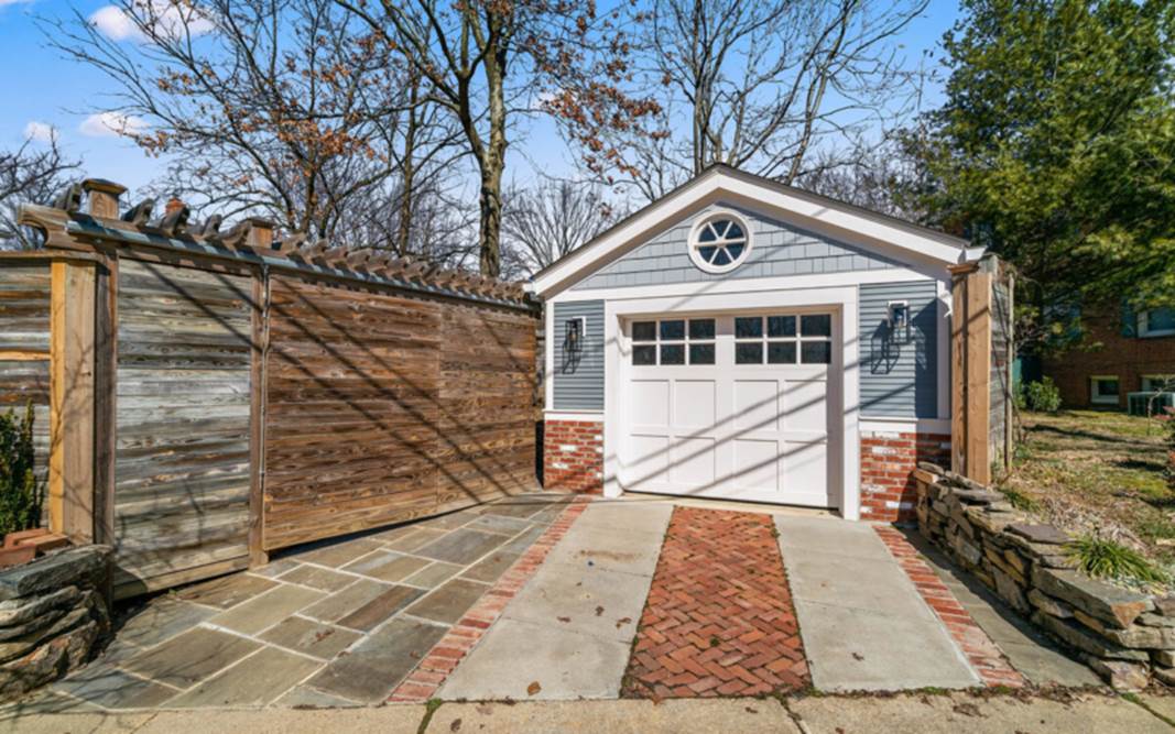 A garage with a fence and a wood fence

Description automatically generated